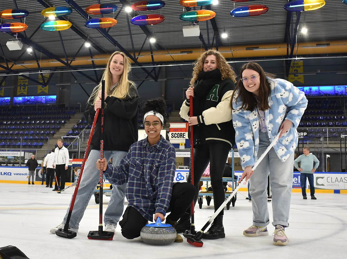 Group of clinic participants with brooms around a curling stone